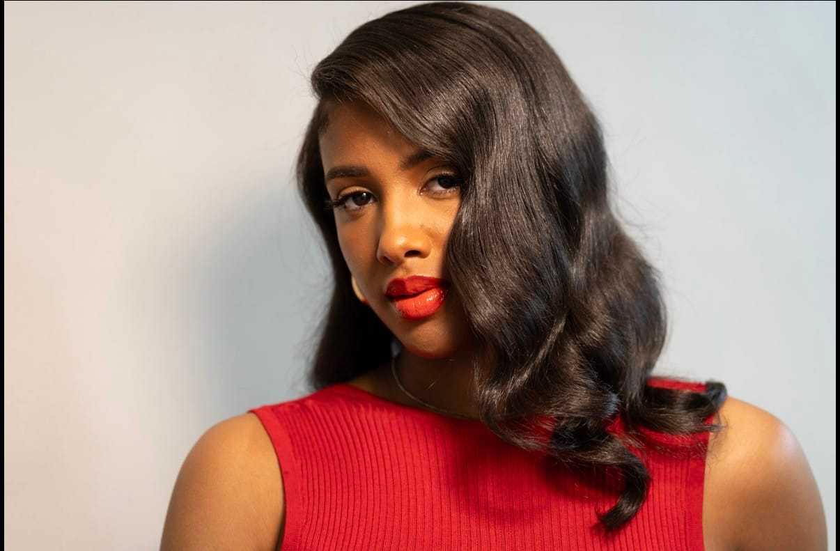 Woman in a red dress with long, wavy hair and red lipstick.